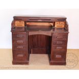 An early 20th century oak roll top desk, with fitted interior above eight drawers, on plinth base,