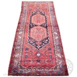 A Caucasian wool carpet / runner, worked with two central medallions against a red ground,
