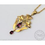 A garnet set Edwardian pendant of sinuous foliate form and with an attached rope twist chain,