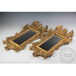 A pair of decorative composite cast and gilt painted wall mirrors,