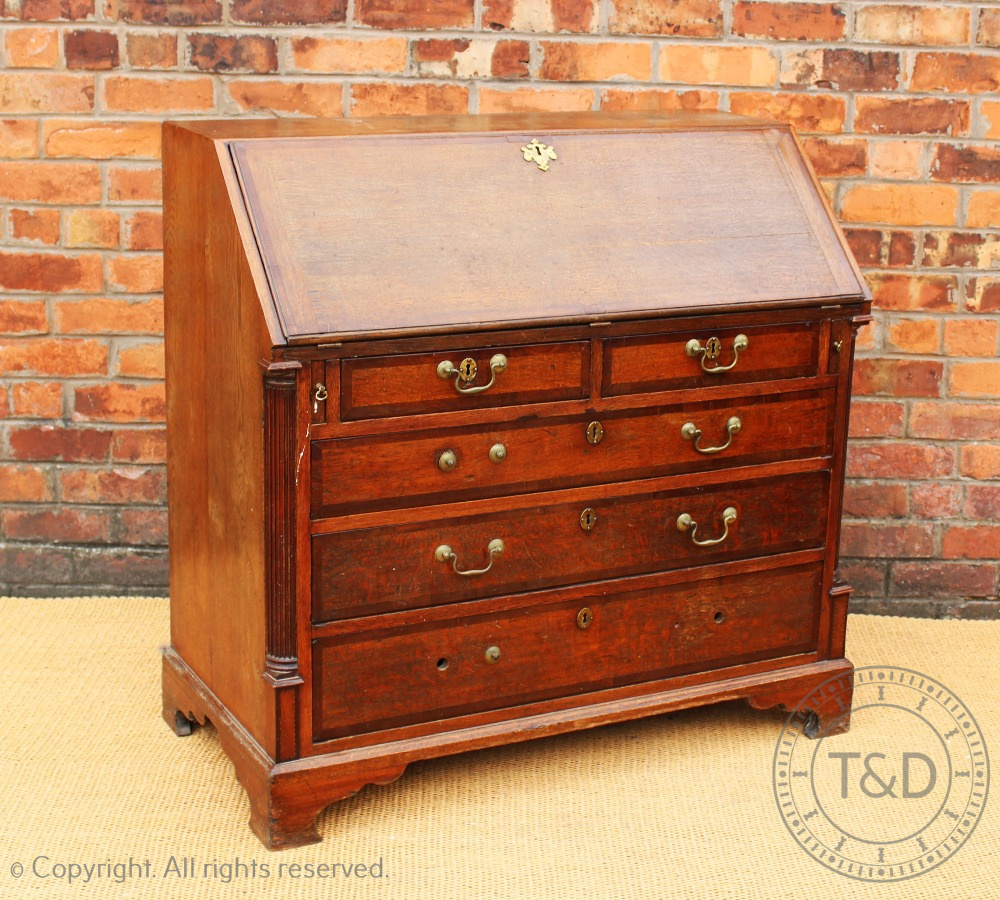 A George III oak and mahogany cross banded bureau, with fall enclosing a fitted interior,