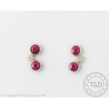 A pair of ruby and diamond set earrings, designed as two rubies centred by a brilliant cut diamond,