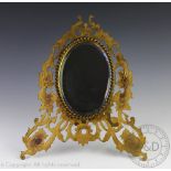 A late Victorian pierced and engraved brass easel mirror, with oval mirror plate,