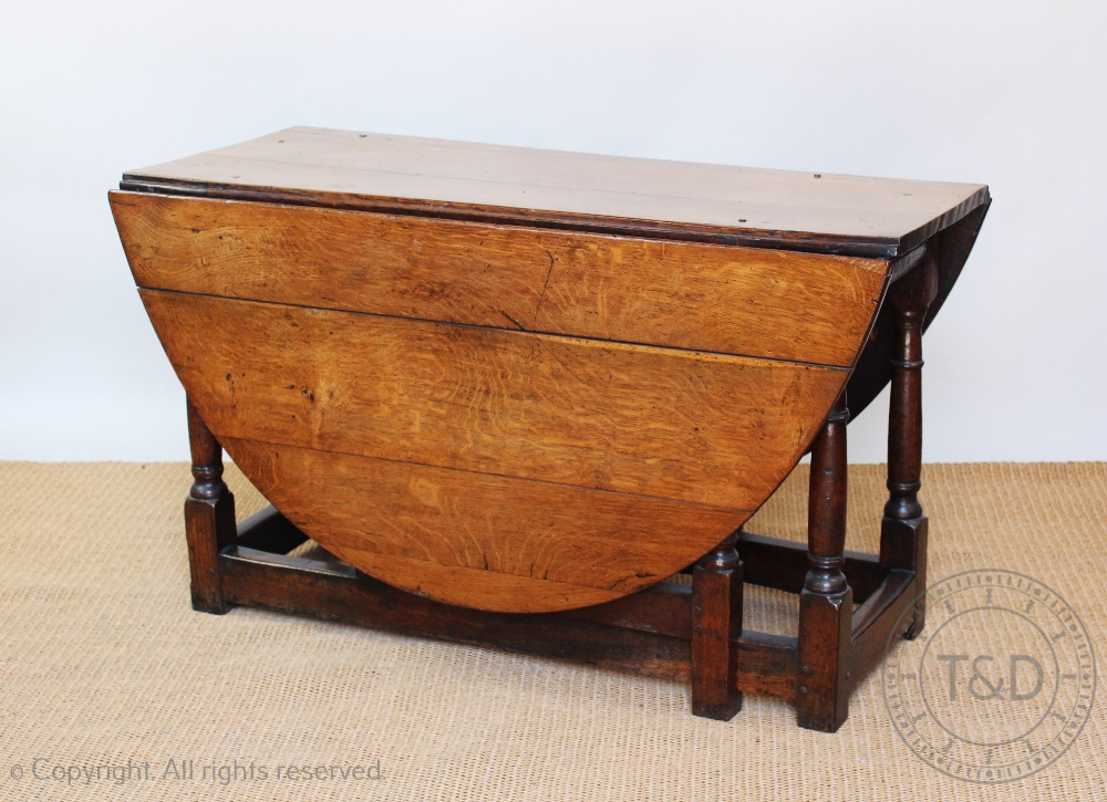 An early 18th century oak gate leg table, with moulded detailing, on turned and block legs,