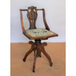 A late Victorian carved and stained beech revolving music chair, with carved and pierced splat,
