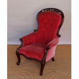 A Victorian carved and pierced mahogany salon chair, with button back red upholstery,