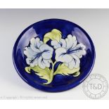 A Moorcroft blue Hibiscus pattern plate, decorated against a blue ground,