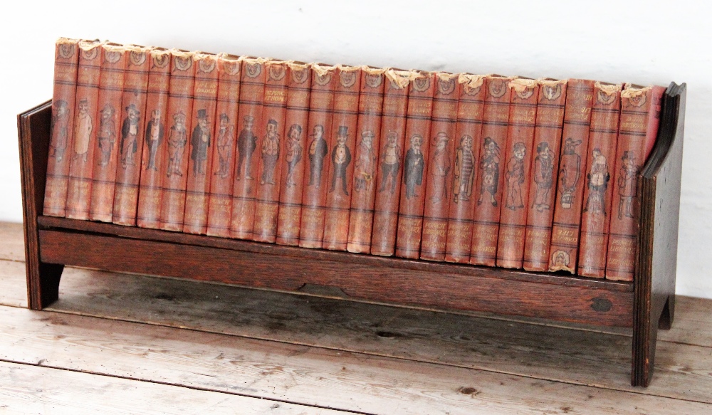 An early 20th century oak book trough, containing twenty four copies of Punch,