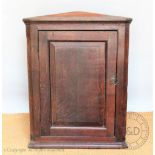 A George III oak hanging corner cupboard, with panelled door,