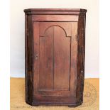 A George III oak corner cabinet, with panelled door enclosing serpentine shelves,