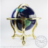 A terrestrial globe inlaid with semi-precious stone, the rotating globe within a brass frame,