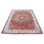 A Kashmir bamboo silk carpet, worked with a large floral medallion against a salmon coloured ground,