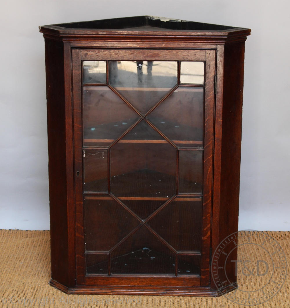 A George III and later oak hanging corner cabinet, with astragal glazed door,