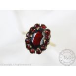 A garnet set oval cluster ring, all set in yellow metal, hoop stamped '333', weight 4.