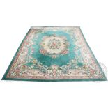 A Chinese wool carpet, worked with a central floral medallion against a turquoise ground,