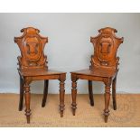 A pair of Victorian carved oak hall chairs, with shield shaped backs and solid seats,