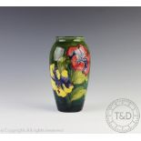 A Moorcroft Hibiscus pattern cylindrical vase, decorated against graded ink and green ground,