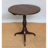 A George III oak occasional table, with three plank top, on a turned column and tripod base,