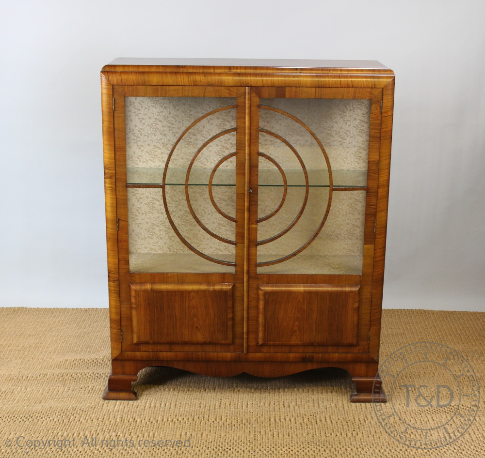 An Art Deco walnut display cabinet, with two glazed doors forming concentric circles,