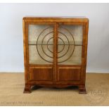 An Art Deco walnut display cabinet, with two glazed doors forming concentric circles,