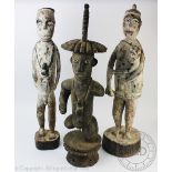 A pair of carved and painted wood tribal figures, male and female, he modelled with a flask,