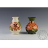 Two Moorcroft Hibiscus pattern vases, decorated against a green and an ivory ground,