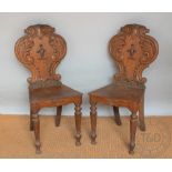A pair of Victorian carved oak crested hall chairs,