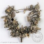A silver charm bracelet, the flat curb link chain hung with numerous silver and white metal charms,