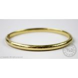 A yellow metal hinged bangle, stamped '585',