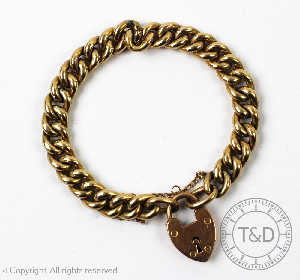 A yellow metal curb link bracelet with an attached padlock clasp stamped '9ct', gross weight 16. - Image 3 of 3