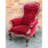 A Victorian carved mahogany salon chair, with scroll end arms and button back red upholstery,