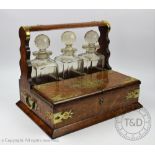 A Victorian oak tantalus, with three cut glass decanters and stoppers and brass strapwork detailing,