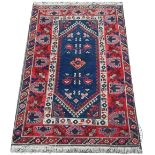 A Caucasian wool rug, worked with geometric motifs against a blue ground,