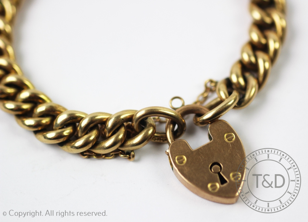 A yellow metal curb link bracelet with an attached padlock clasp stamped '9ct', gross weight 16. - Image 2 of 3