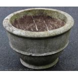 A reconstituted stone circular garden planter of plain banded design,