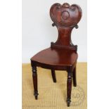 A Regency carved mahogany hall chair, with scroll back and solid seat,