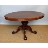 A Victorian mahogany oval loo table, with turned and carved baluster column and four scroll legs,