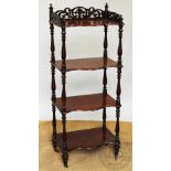 An early Victorian mahogany serpentine four tier whatnot, with fret cut three quarter gallery,