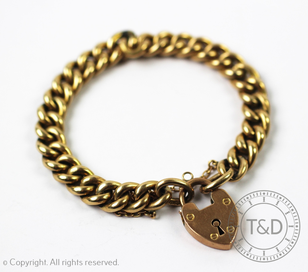 A yellow metal curb link bracelet with an attached padlock clasp stamped '9ct', gross weight 16.