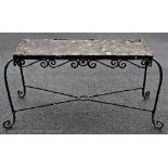 A garden table on scrolling metal base with concrete top,