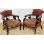 A pair of late Victorian carved walnut tub chairs, with brown upholstery, on cabriole legs,