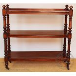 A Victorian mahogany three tier buffet, with turned baluster supports and brass casters,