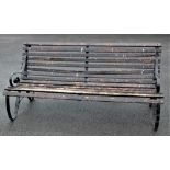 A scroll end garden bench with wooden slatted seat,