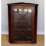 A George III and later oak hanging corner cabinet, with astragal glazed door,