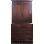 An early 19th century oak cabinet on chest, with two panelled doors enclosing shelves,