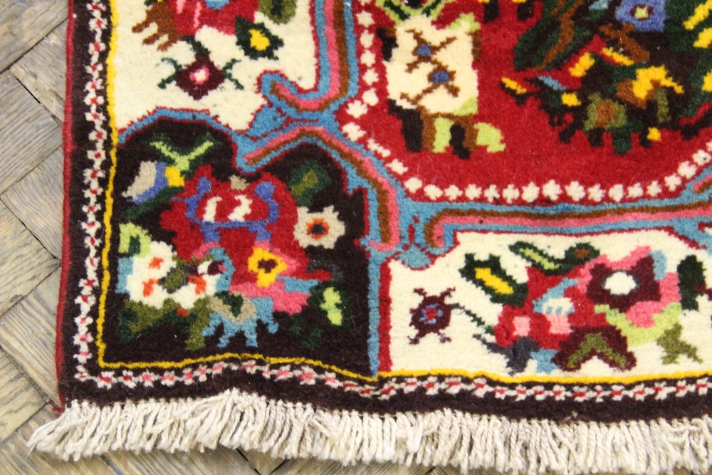 A Persian full pile wool rug, worked with a central floral spray, - Bild 2 aus 4