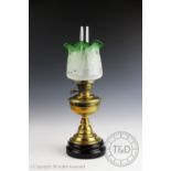 A late Victorian oil lamp with baluster brass stem supporting a green frosted florally etched shade