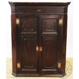 A George III oak hanging corner cupboard, with dentil cornice and two panelled doors,