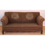 An Edwardian salon settee, with floral green upholstery, on tapered square legs,