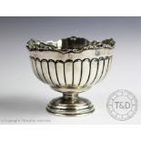 A white metal pedestal bowl, of fluted form and with cast scrolling rim on stepped circular foot,